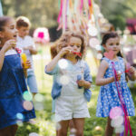 Small children outdoors in garden in summer, playing with bubbles.